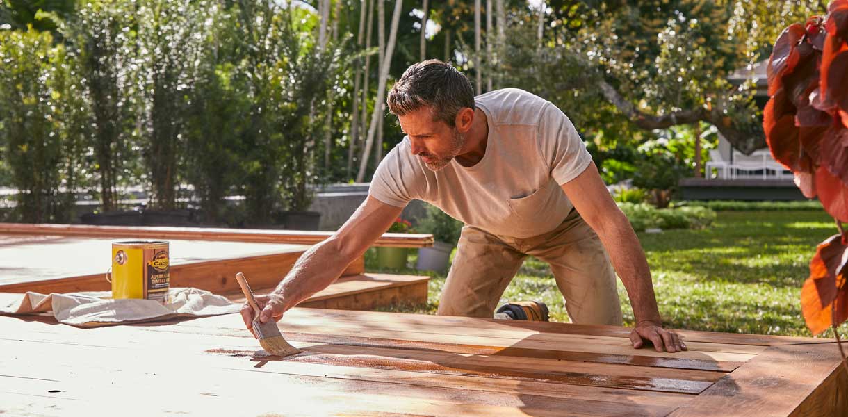 person staining a deck outside