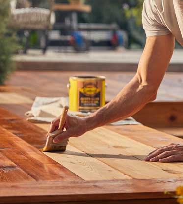 person staining a deck outside