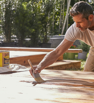 person staining a deck outside